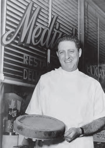 Milt Medine shows off his famous cheesecake, c. 1956